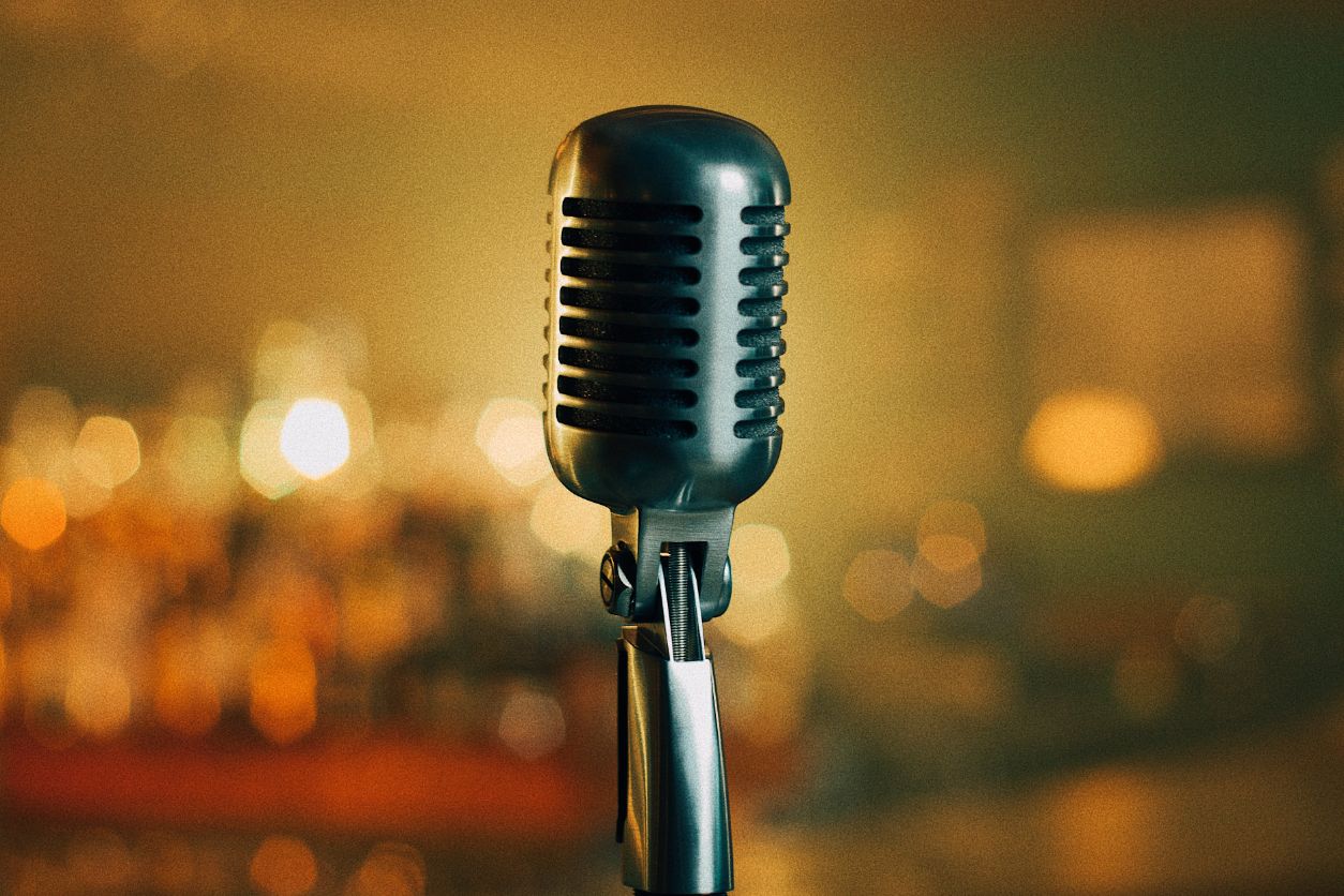 A microphone is on the stand in front of blurry lights.
